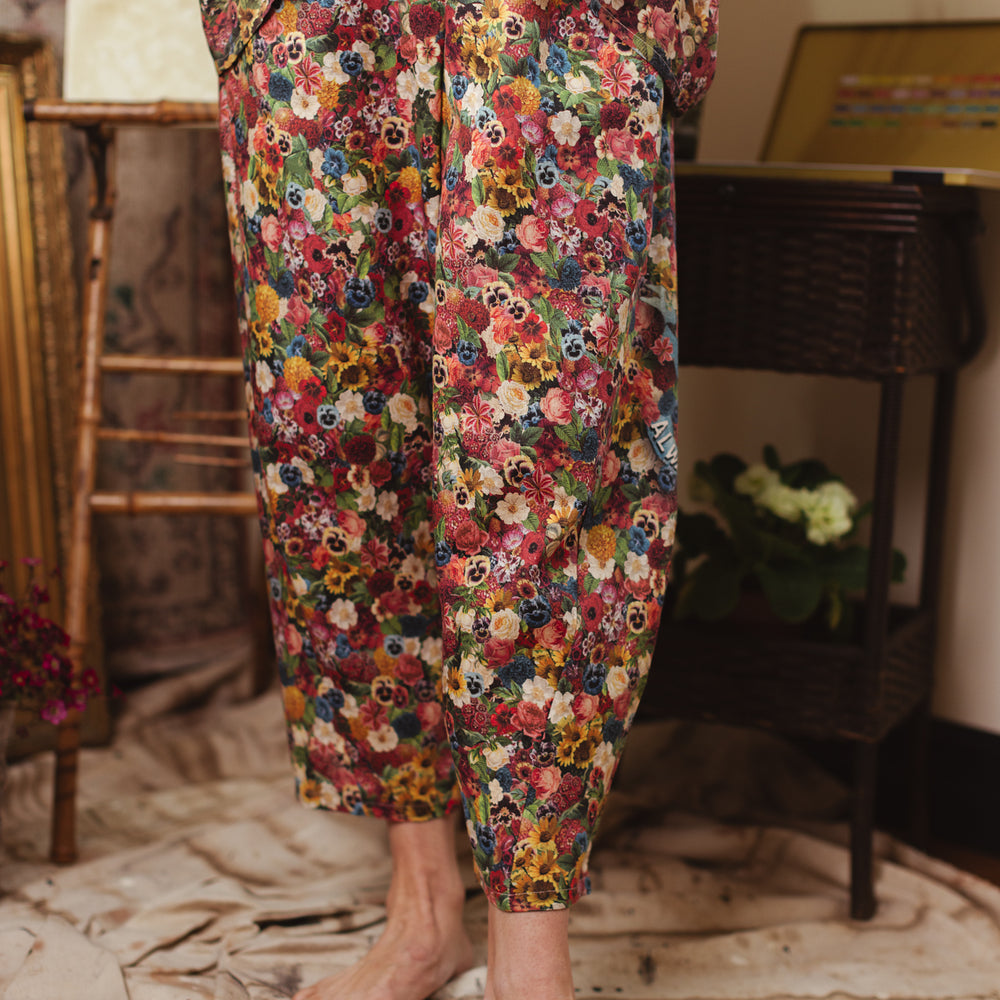 
                  
                    Artist pants featuring a whimsical print of 50 antique seed catalogue flowers arranged on a painter’s palette with a Monet quote – Market of Stars.
                  
                