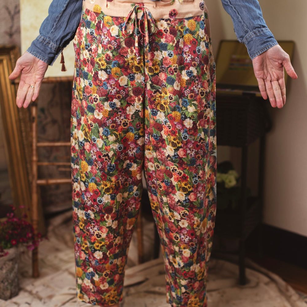 
                  
                    Artist pants featuring a whimsical print of 50 antique seed catalogue flowers arranged on a painter’s palette with a Monet quote – Market of Stars.
                  
                