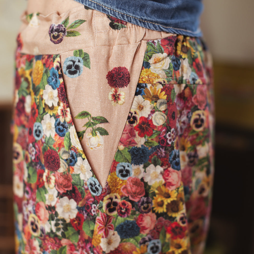 
                  
                    Artist pants featuring a whimsical print of 50 antique seed catalogue flowers arranged on a painter’s palette with a Monet quote – Market of Stars.
                  
                