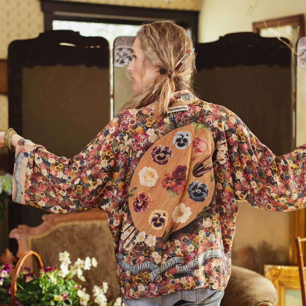 
                  
                    Short kimono featuring a whimsical artist’s palette and over 50 layered flowers from antique seed catalogues, inspired by Claude Monet – Market of Stars.
                  
                