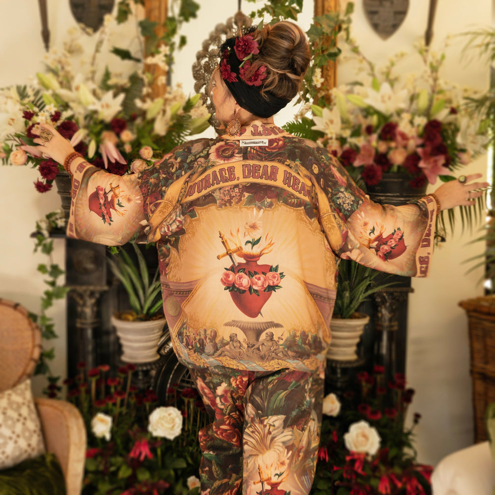 
                  
                    Model wearing Courage Dear Heart Pixie cut Duster featuring Victorian Sacred Heart art and hidden affirmations of courage and love on bamboo-based viscose – Market of Stars.
                  
                