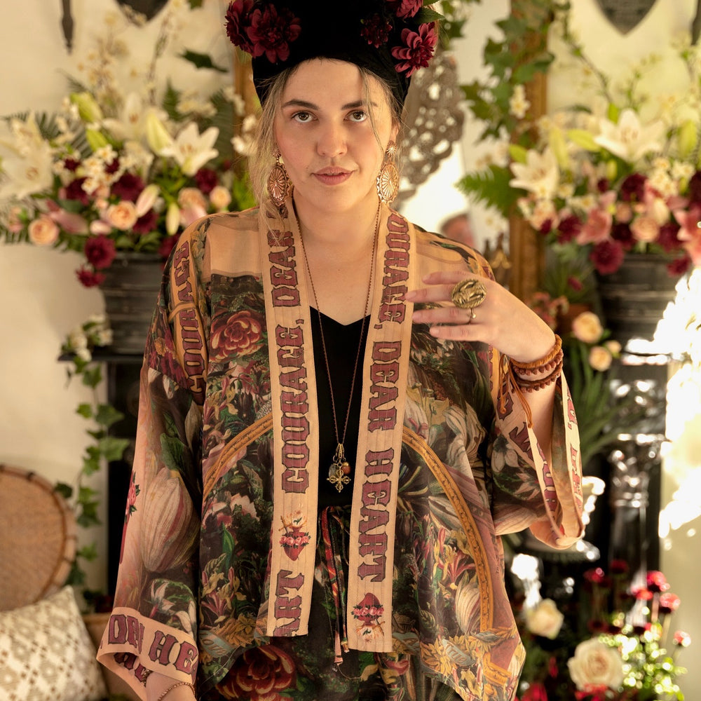 
                  
                    Model wearing Courage Dear Heart Pixie cut Duster featuring Victorian Sacred Heart art and hidden affirmations of courage and love on bamboo-based viscose – Market of Stars.
                  
                