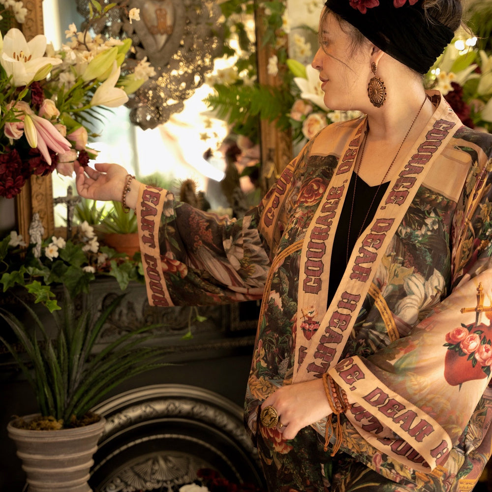 
                  
                    Model wearing Courage Dear Heart Pixie cut Duster featuring Victorian Sacred Heart art and hidden affirmations of courage and love on bamboo-based viscose – Market of Stars.
                  
                