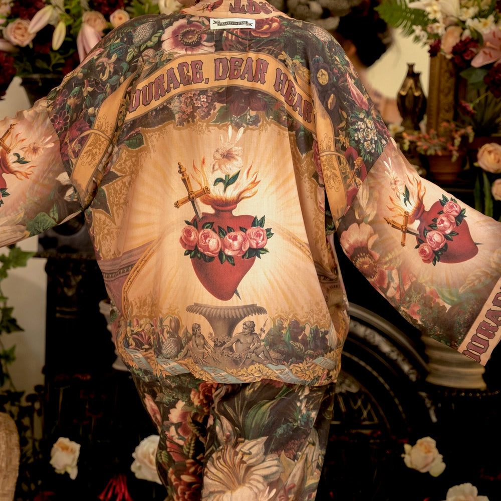 
                  
                    Model wearing Courage Dear Heart Pixie cut Duster featuring Victorian Sacred Heart art and hidden affirmations of courage and love on bamboo-based viscose – Market of Stars.
                  
                