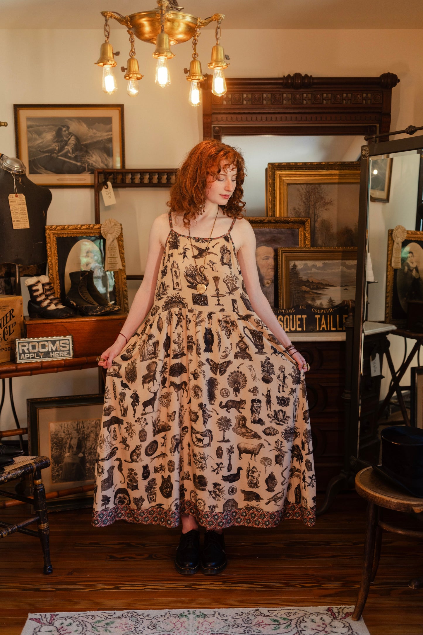 Model wearing a maxi-length bamboo viscose slip dress inspired by a mysterious Victorian scrapbook. This whimsical print celebrates the wonder hidden in ordinary things — Market of Stars.