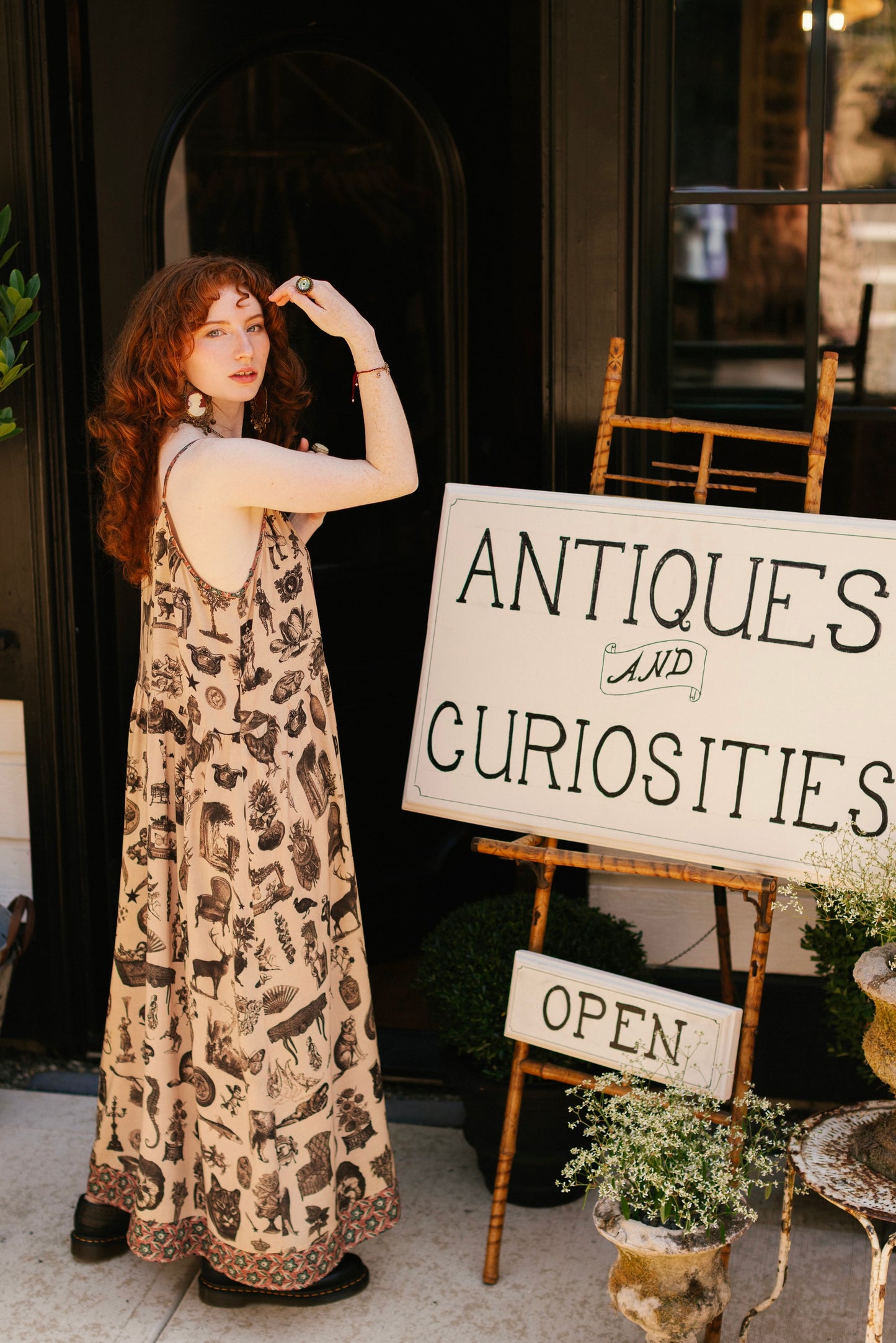 Model wearing a maxi-length bamboo viscose slip dress inspired by a mysterious Victorian scrapbook. This whimsical print celebrates the wonder hidden in ordinary things — Market of Stars.