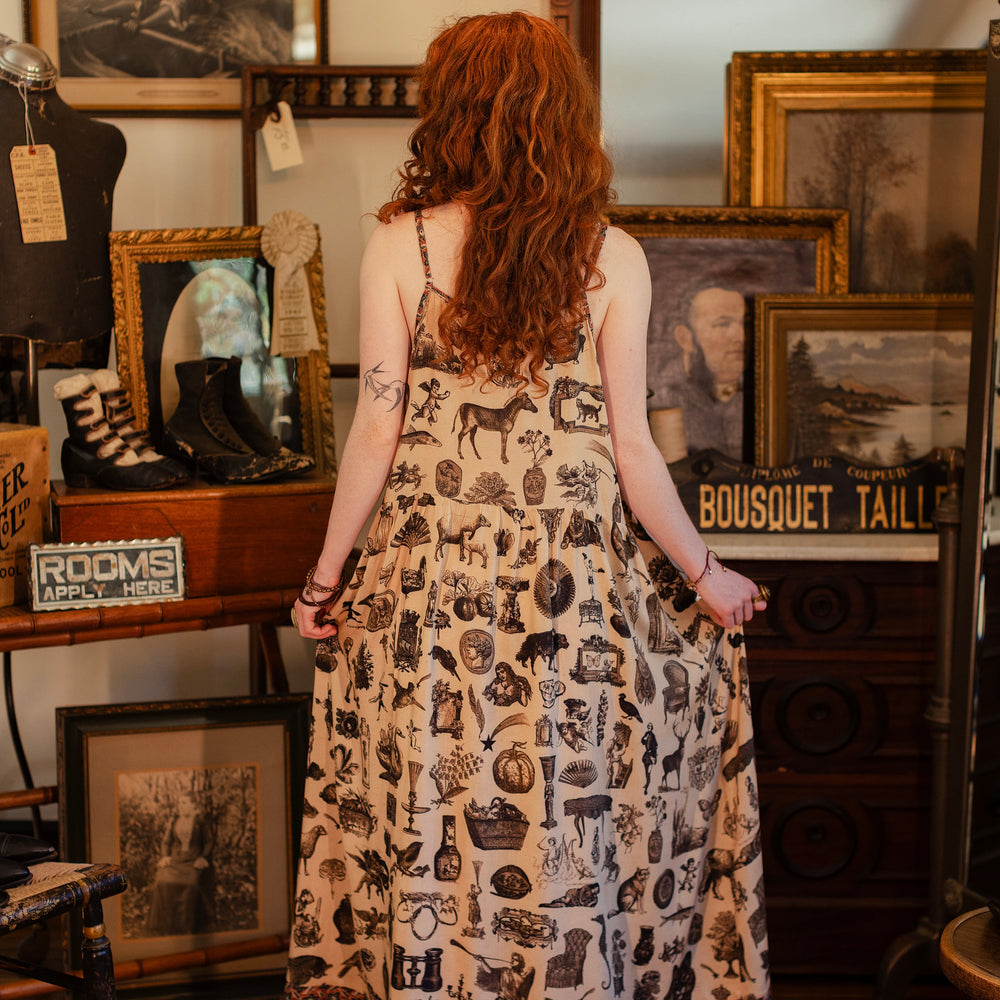 
                  
                    Model wearing a maxi-length bamboo viscose slip dress inspired by a mysterious Victorian scrapbook. This whimsical print celebrates the wonder hidden in ordinary things — Market of Stars.
                  
                