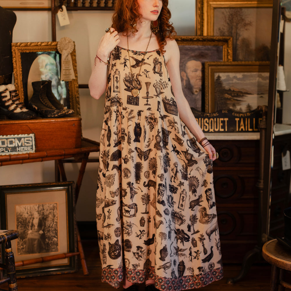 
                  
                    Model wearing a maxi-length bamboo viscose slip dress inspired by a mysterious Victorian scrapbook. This whimsical print celebrates the wonder hidden in ordinary things — Market of Stars.
                  
                