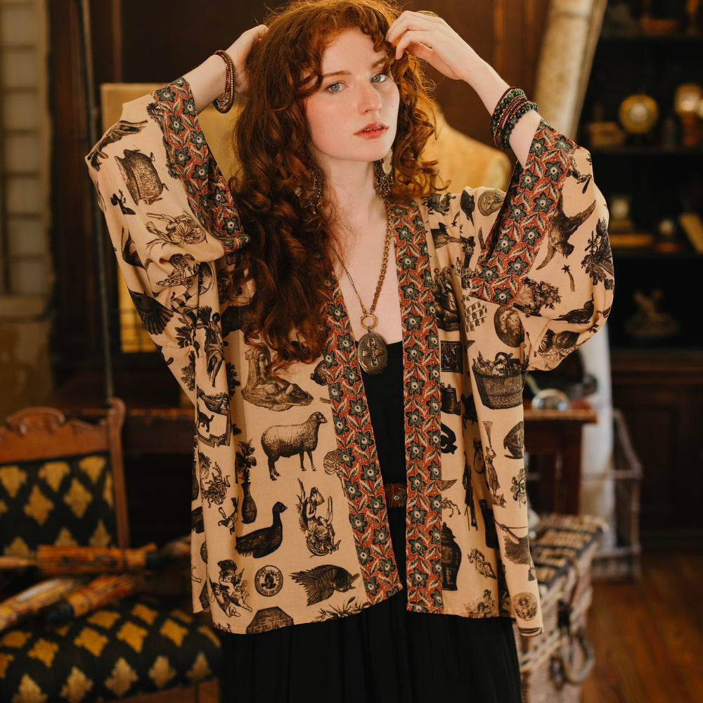Model wearing a bamboo-viscose cropped length duster inspired by a mysterious Victorian scrapbook. This whimsical print celebrates the wonder hidden in ordinary things — Market of Stars.