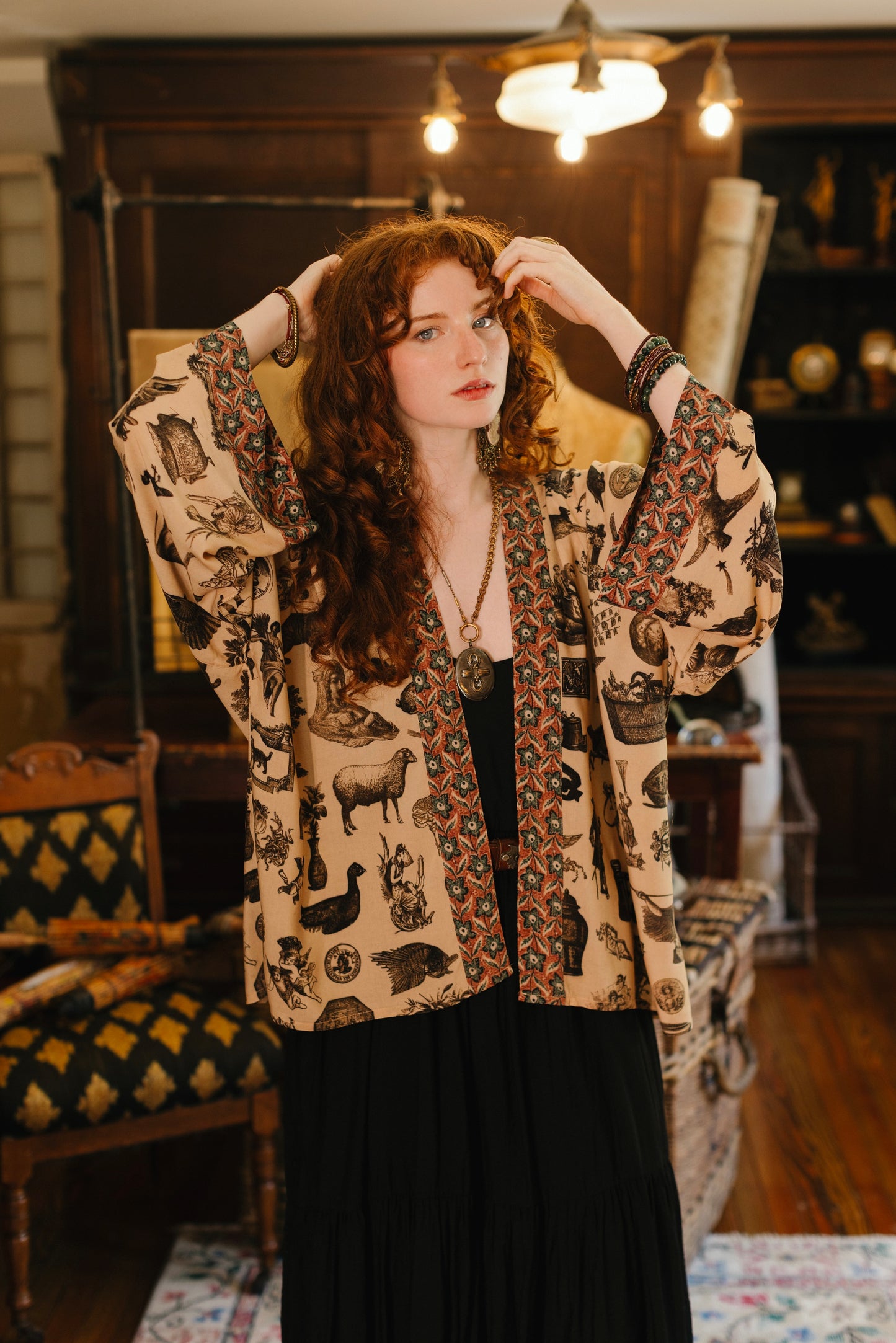 Model wearing a bamboo-viscose cropped length duster inspired by a mysterious Victorian scrapbook. This whimsical print celebrates the wonder hidden in ordinary things — Market of Stars.