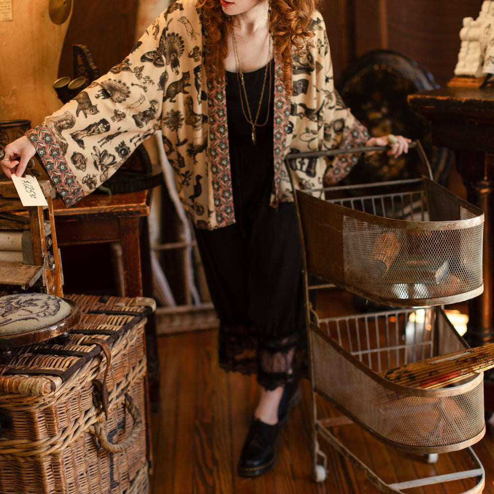 
                  
                    Model wearing a bamboo-viscose cropped length duster inspired by a mysterious Victorian scrapbook. This whimsical print celebrates the wonder hidden in ordinary things — Market of Stars.
                  
                