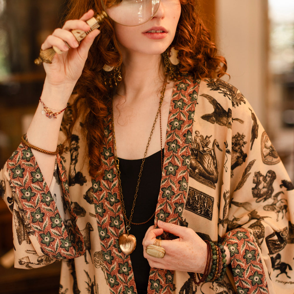 
                  
                    Model wearing a bamboo-viscose cropped length duster inspired by a mysterious Victorian scrapbook. This whimsical print celebrates the wonder hidden in ordinary things — Market of Stars.
                  
                