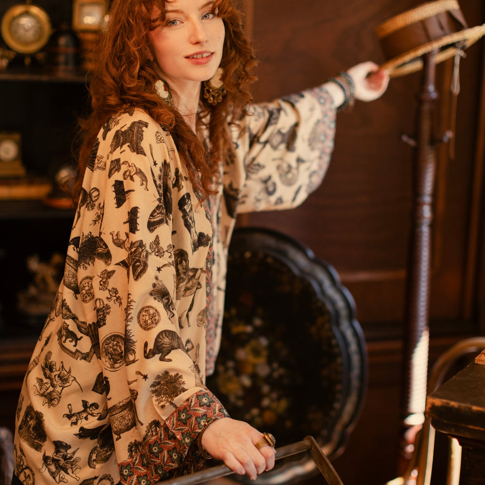 
                  
                    Model wearing a bamboo-viscose cropped length duster inspired by a mysterious Victorian scrapbook. This whimsical print celebrates the wonder hidden in ordinary things — Market of Stars.
                  
                