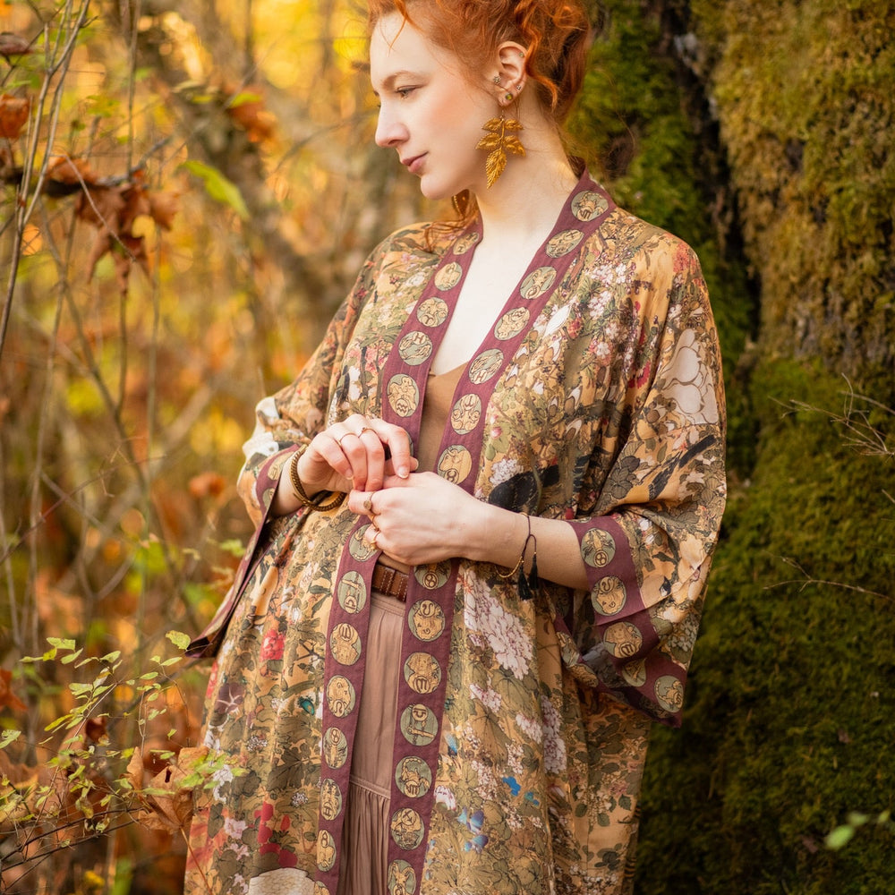 Model wearing Dreamweaver Opera Duster – featuring Alphonse Mucha’s zodiac woman, celestial crown, and burgundy zodiac trim inspired by 1970s luxe bohemian style – Market of Stars.