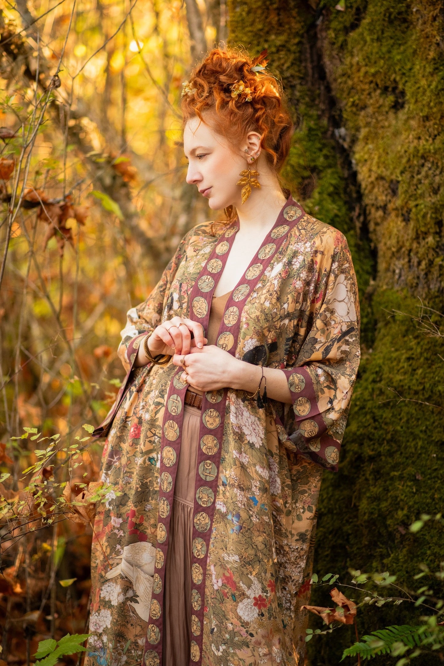 Model wearing Dreamweaver Opera Duster – featuring Alphonse Mucha’s zodiac woman, celestial crown, and burgundy zodiac trim inspired by 1970s luxe bohemian style – Market of Stars.