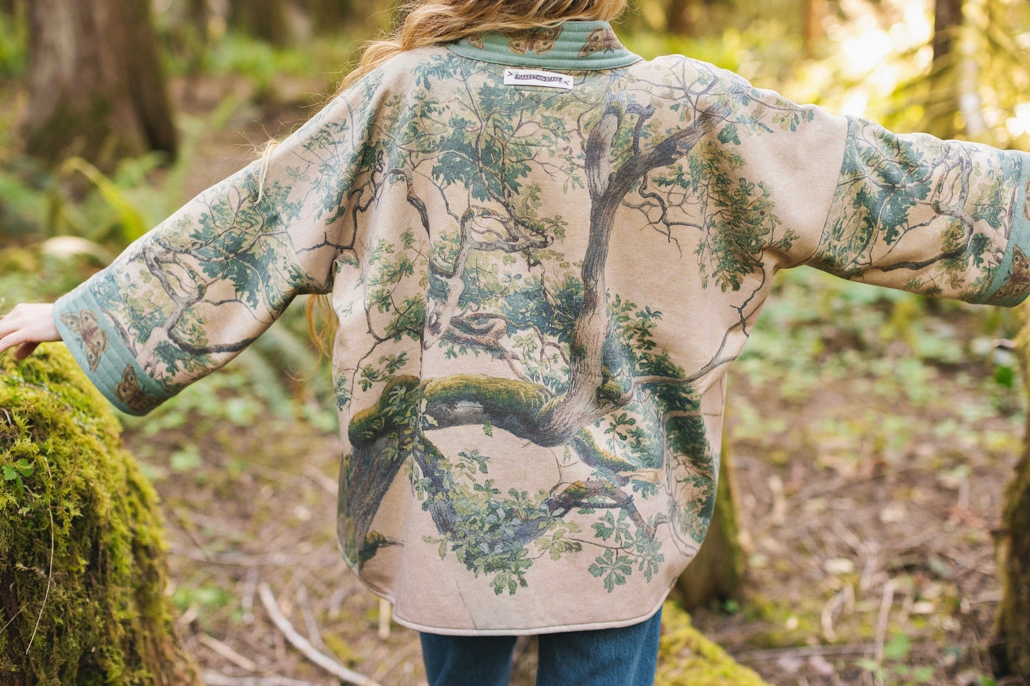 Model wearing Earth and Sky Cottage Jacket – featuring Charles Aston’s tree painting and antique moth art – cozy fleece-lined cardigan for cooler days – Market of Stars.
