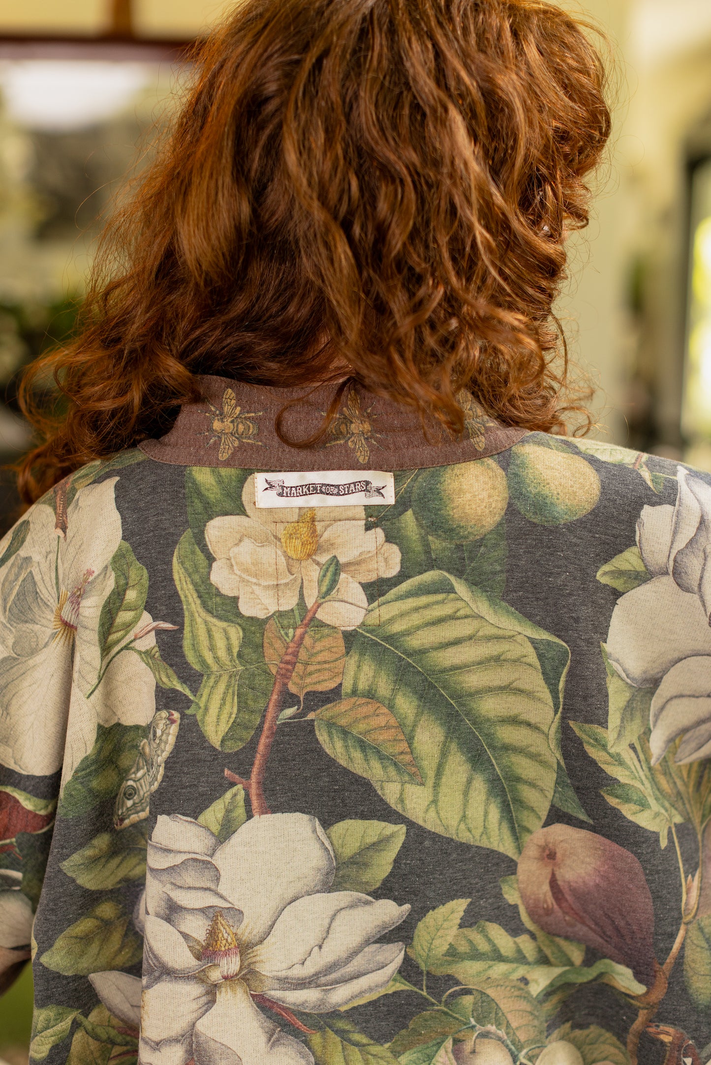 Model wearing a cozy cardigan lined with fleece featuring vintage magnolia lithographs, delicate moth etchings, and charming bumblebee trim - Market of stars