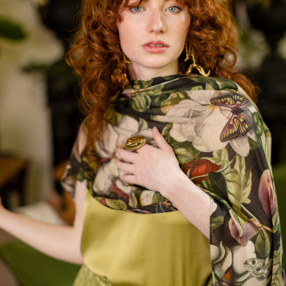 Model wearing a lightweight bamboo viscose scarf featuring vintage magnolia lithographs, delicate moth etchings and charming bumblebee trim - Market of Stars