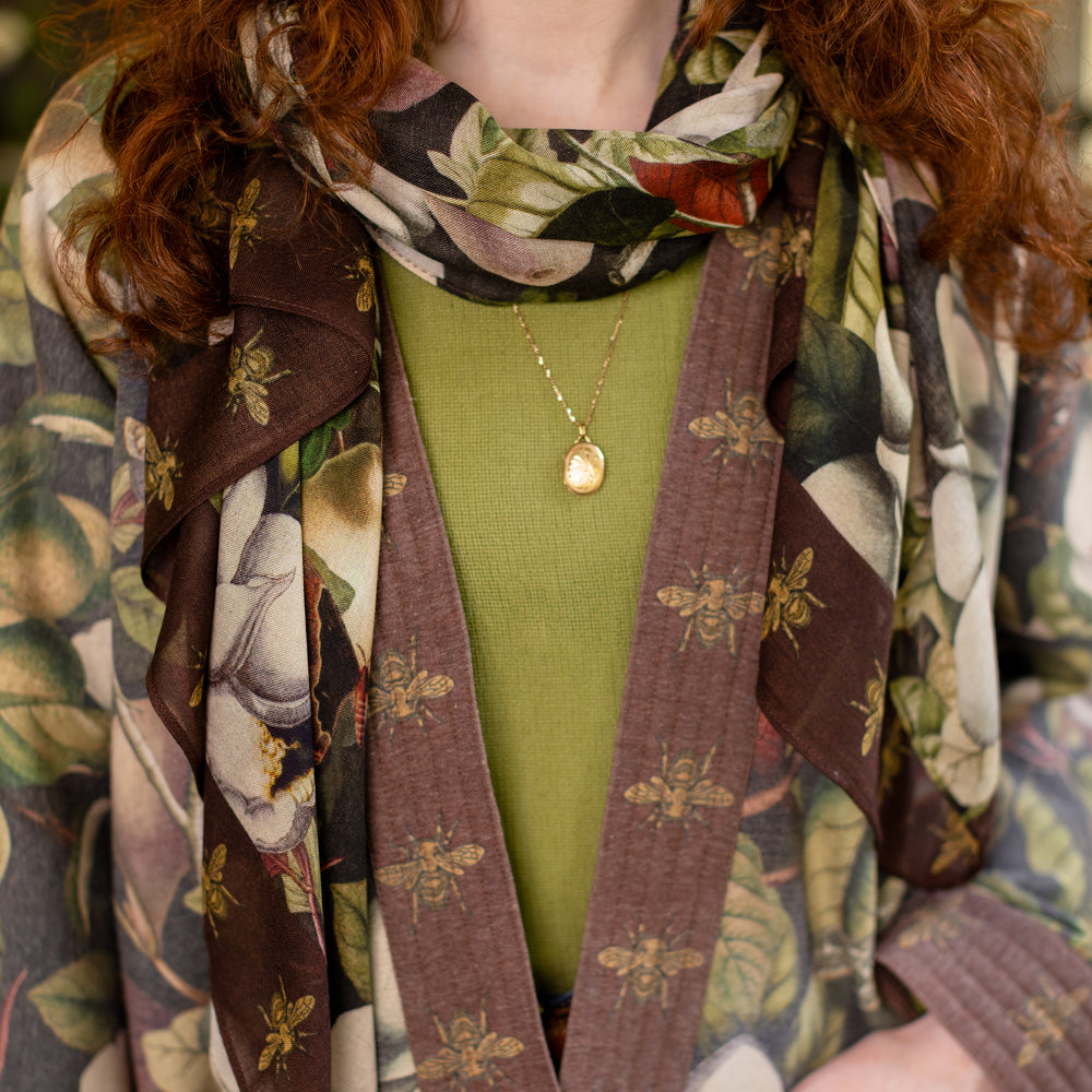 
                  
                    Model wearing a lightweight bamboo viscose scarf featuring vintage magnolia lithographs, delicate moth etchings and charming bumblebee trim - Market of Stars
                  
                