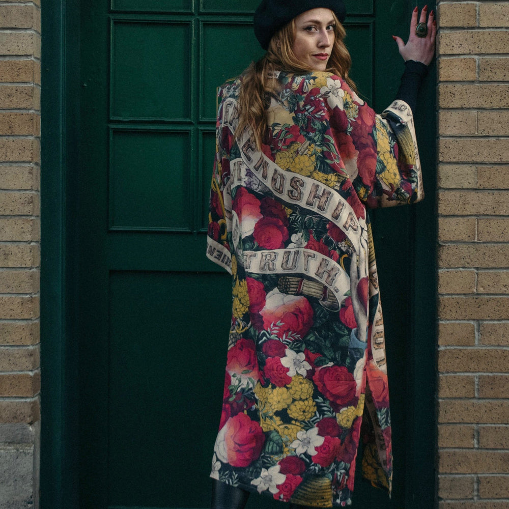 Model wearing our long, eclectic opera duster featuring vintage symbols of love, kindness, and truth in a bold archive-inspired print with removable belt – Market of Stars.