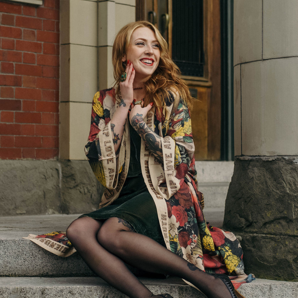 Model wearing our long, eclectic opera duster featuring vintage symbols of love, kindness, and truth in a bold archive-inspired print with removable belt – Market of Stars.