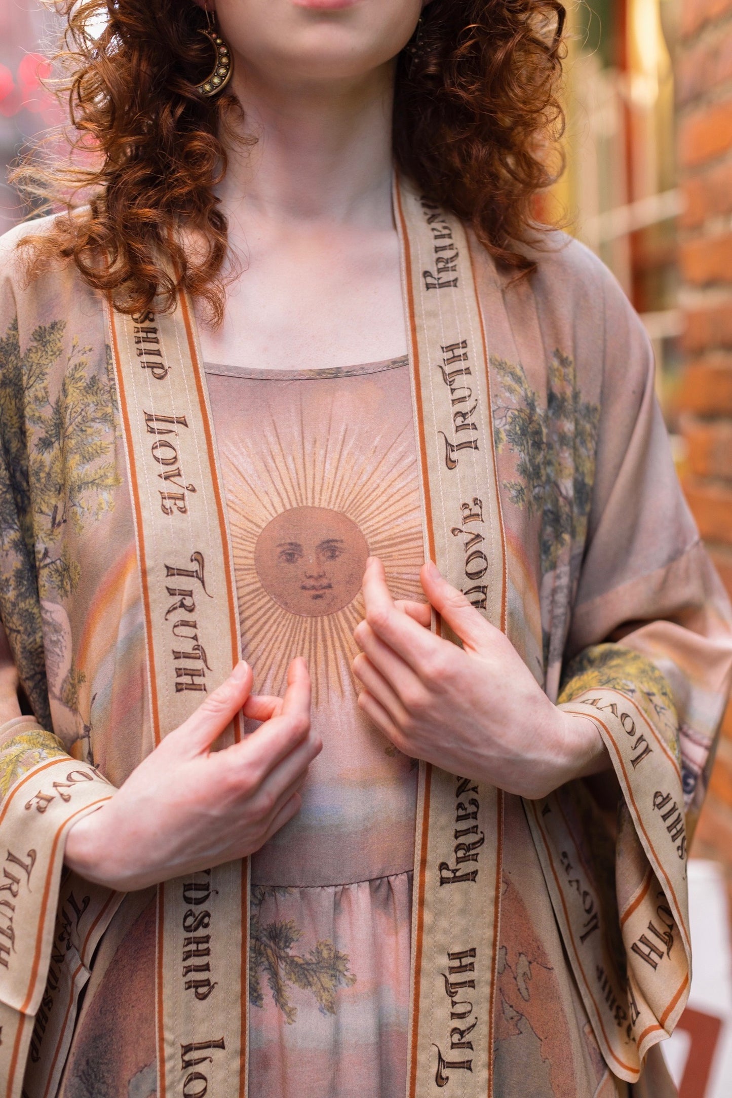 Model wearing sun-washed Bohéme slip dress featuring historic symbols of friendship, love, and truth in soft lavender, sage, gold, and aqua – Market of Stars.