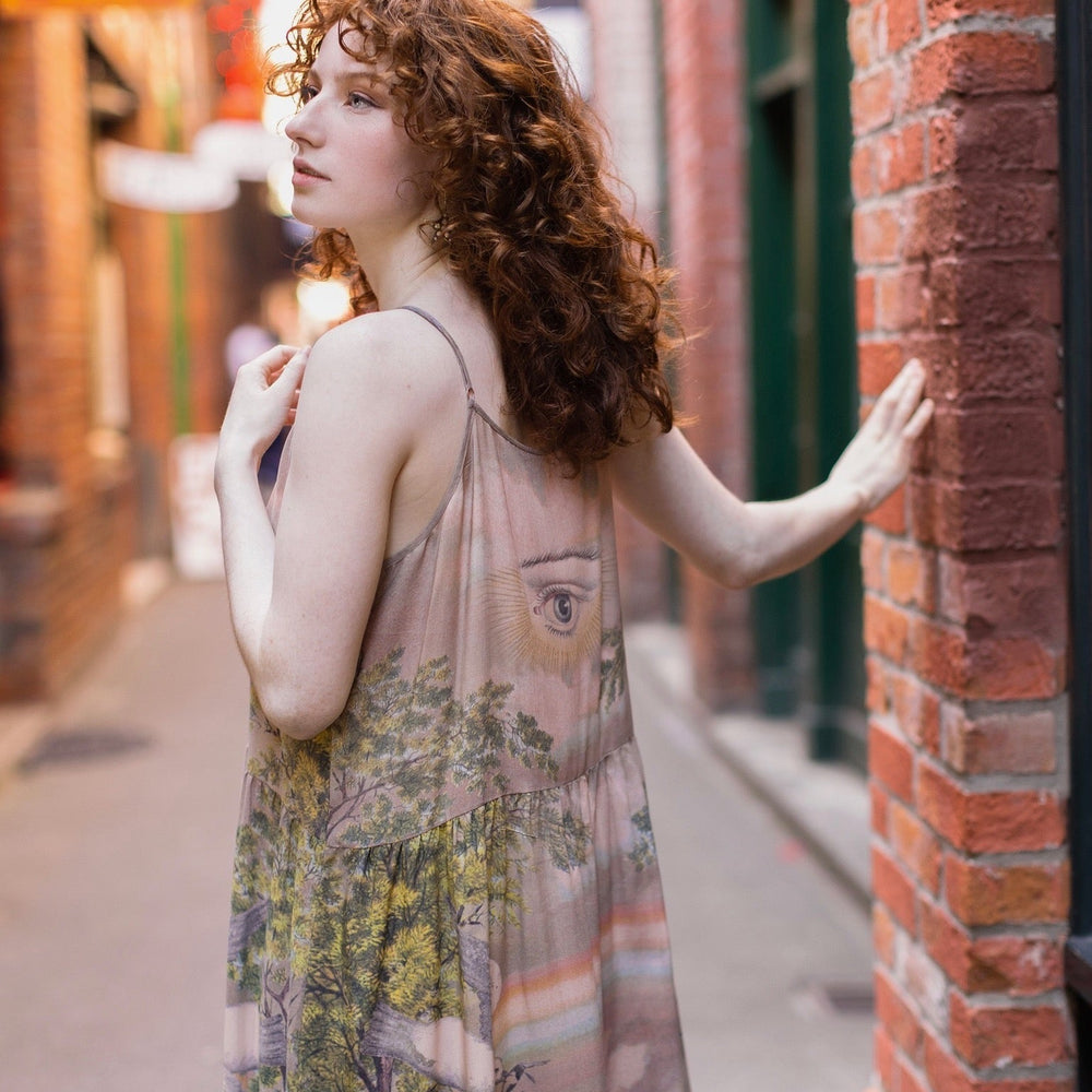 
                  
                    Model wearing sun-washed Bohéme slip dress featuring historic symbols of friendship, love, and truth in soft lavender, sage, gold, and aqua – Market of Stars.
                  
                