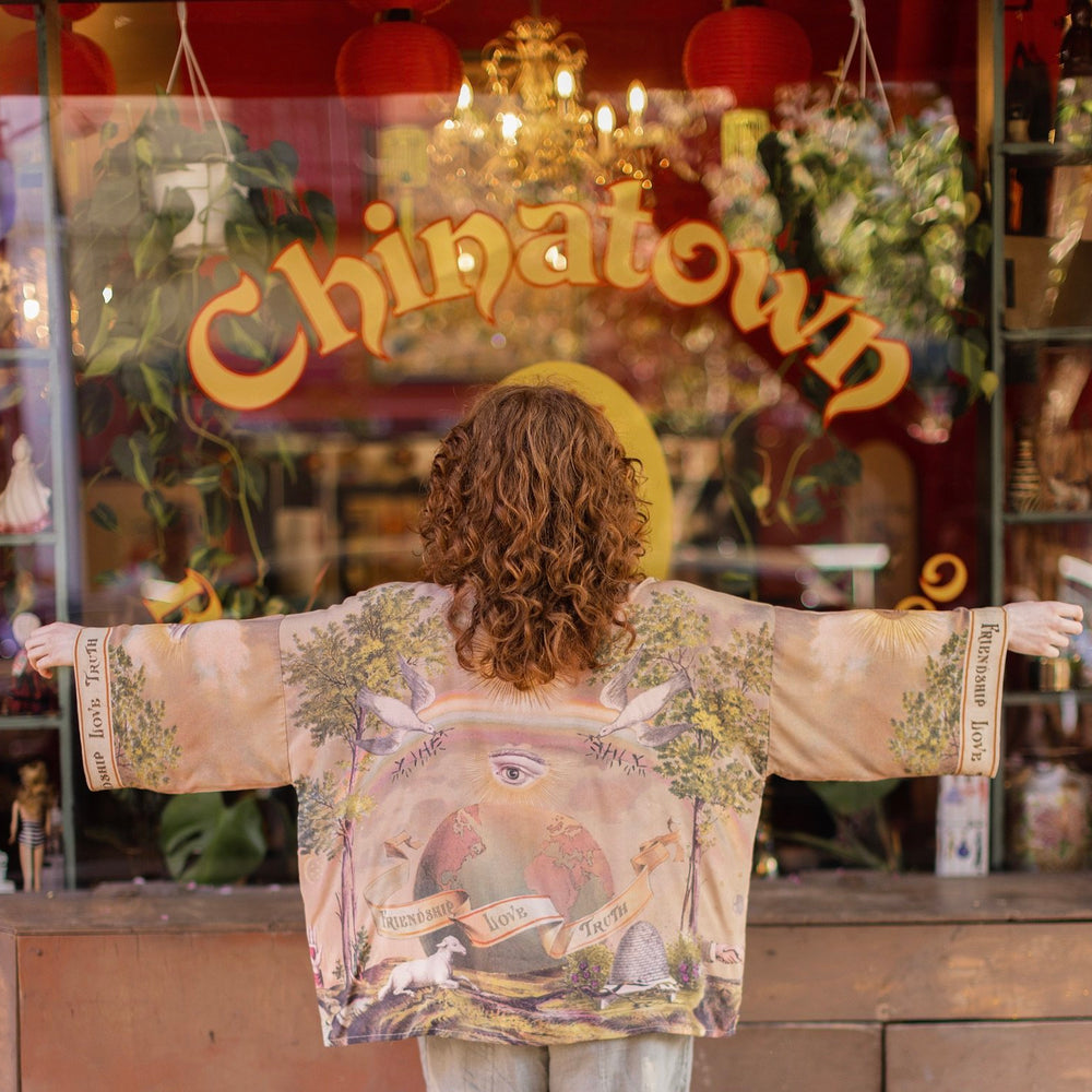 
                  
                    Vintage-inspired cropped kimono featuring historic symbols of friendship, love, and truth in a soft sun-washed palette of lavender, sage, gold, and aqua – Market of Stars.
                  
                