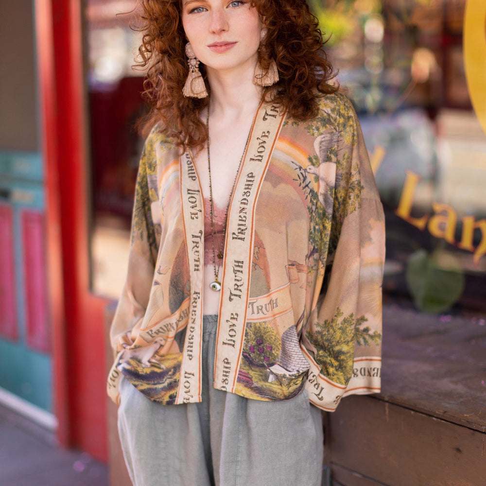 
                  
                    Vintage-inspired cropped kimono featuring historic symbols of friendship, love, and truth in a soft sun-washed palette of lavender, sage, gold, and aqua – Market of Stars.
                  
                