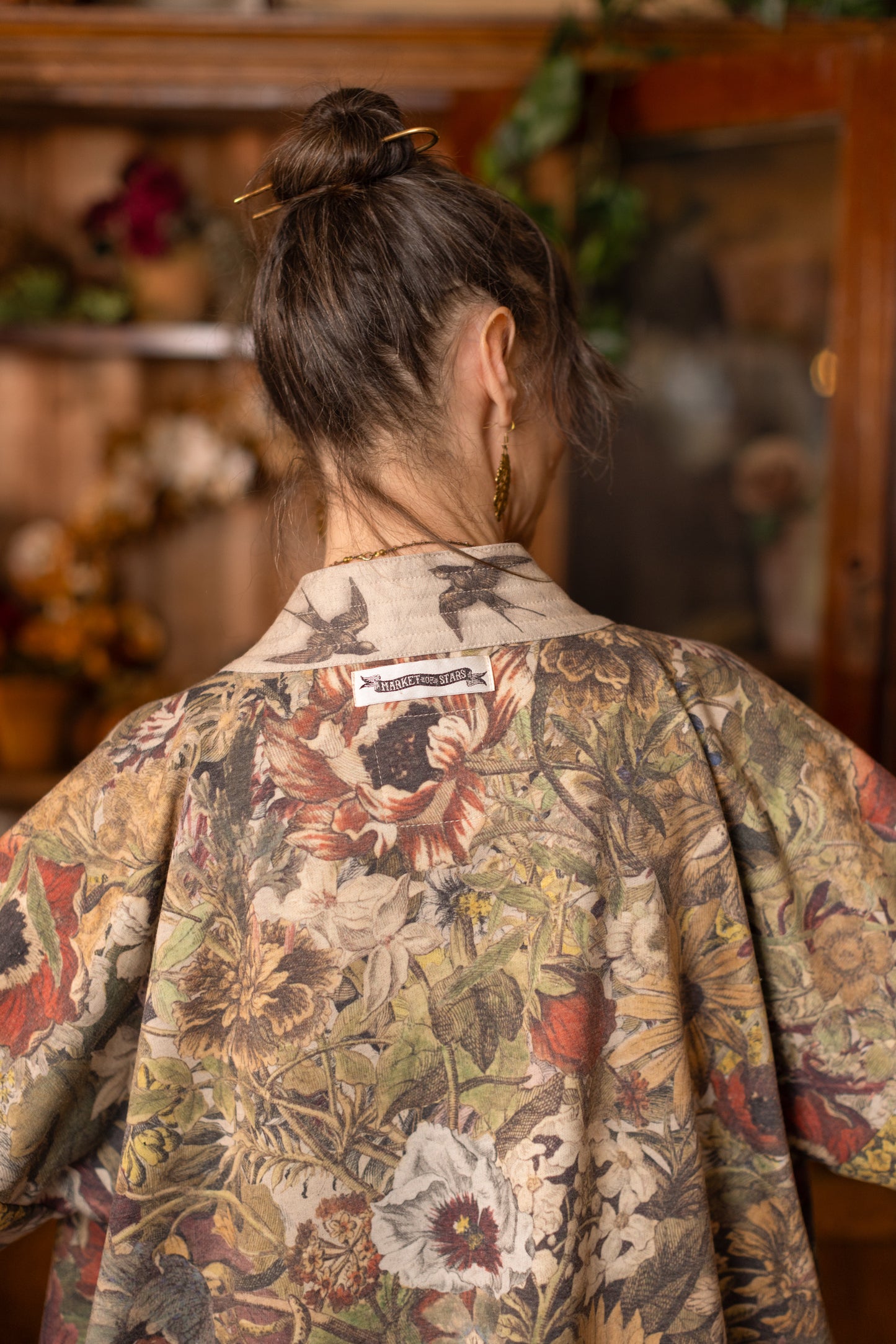Model wearing a soft fleece cottage cardigan featuring rich 1700s botanical blooms and swallow trim - Market of Stars