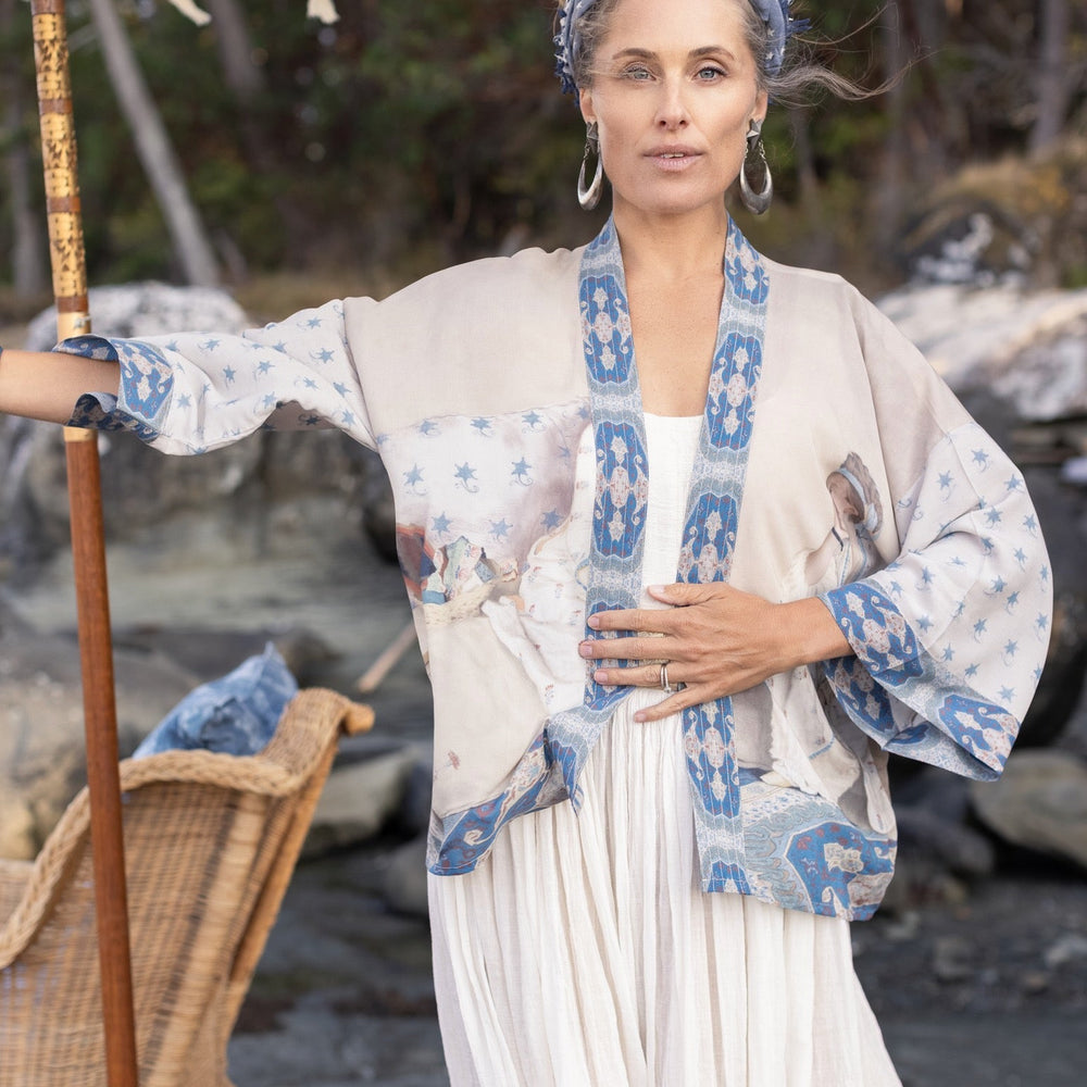 
                  
                    Model wearing the Head in the Clouds Opera Duster featuring Liotard’s portrait of his wife with Turkish textiles, starry sleeves, and poetic script – Market of Stars.
                  
                