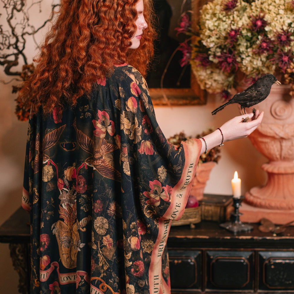 
                  
                    Model wearing a flowy bamboo-viscose duster featuring a collage of antique artwork with romance, loyalty, and old-world beauty - Market of Stars
                  
                