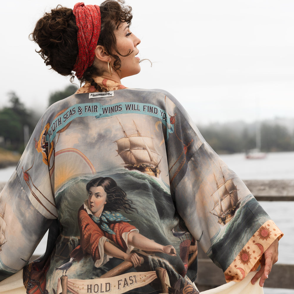 Model wearing the Hold Fast Pixie Duster featuring a Victorian woman rowing through a storm, seagulls, and rainbow horizon – Market of Stars.