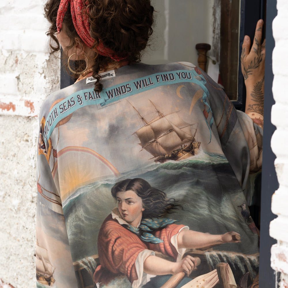 
                  
                    Model wearing the Hold Fast Pixie Duster featuring a Victorian woman rowing through a storm, seagulls, and rainbow horizon – Market of Stars.
                  
                