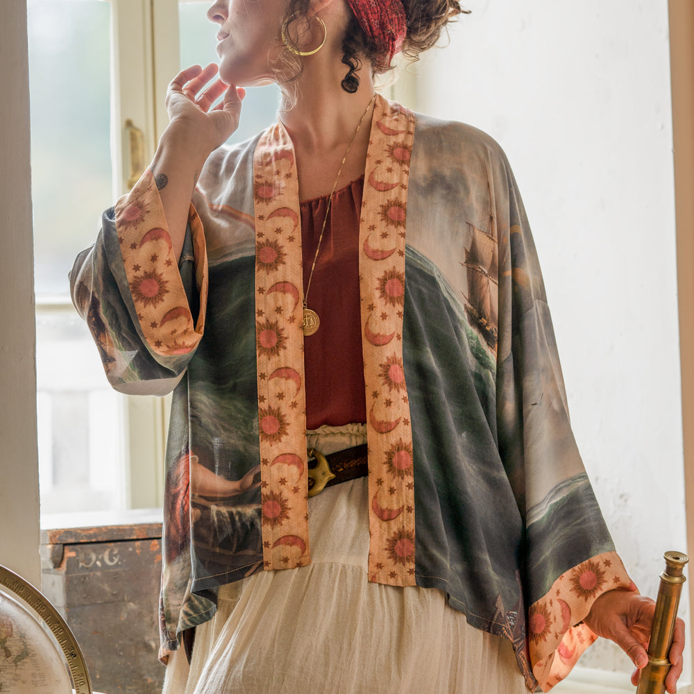 
                  
                    Model wearing the Hold Fast Pixie Duster featuring a Victorian woman rowing through a storm, seagulls, and rainbow horizon – Market of Stars.
                  
                