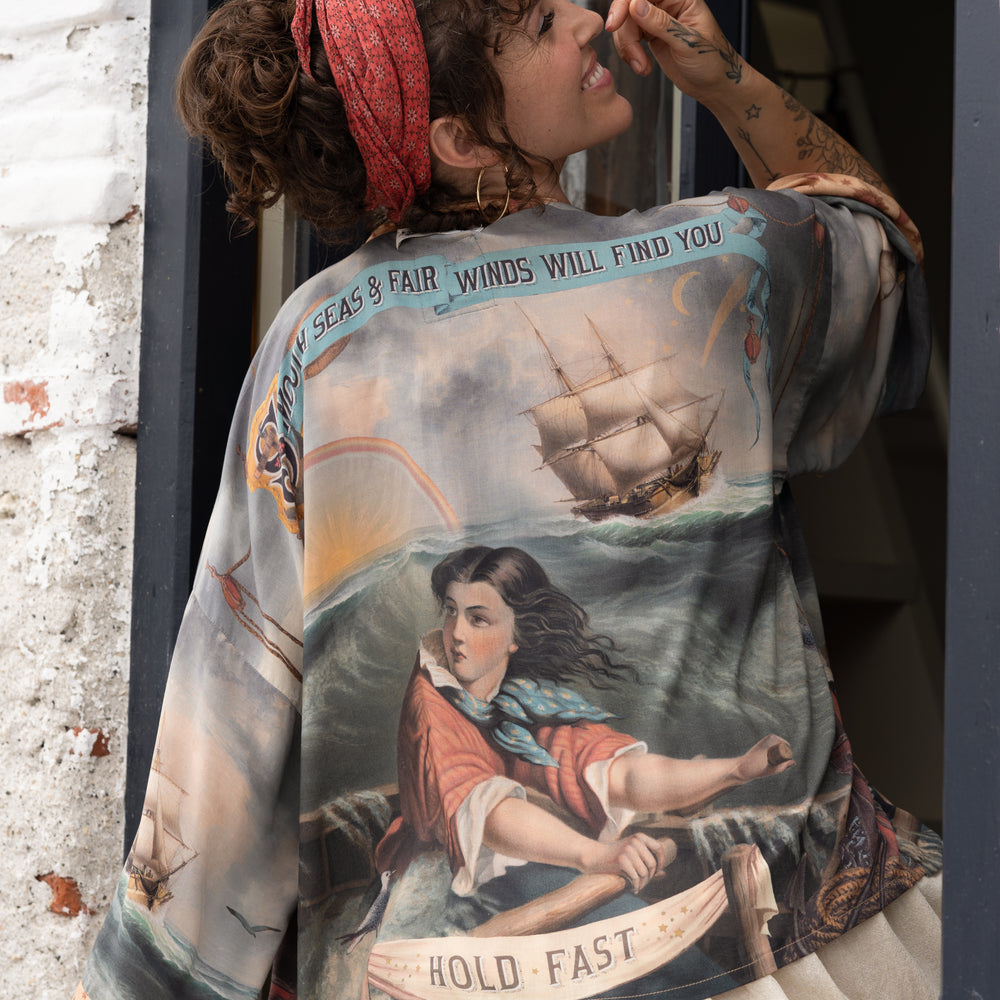 
                  
                    Model wearing the Hold Fast Pixie Duster featuring a Victorian woman rowing through a storm, seagulls, and rainbow horizon – Market of Stars.
                  
                