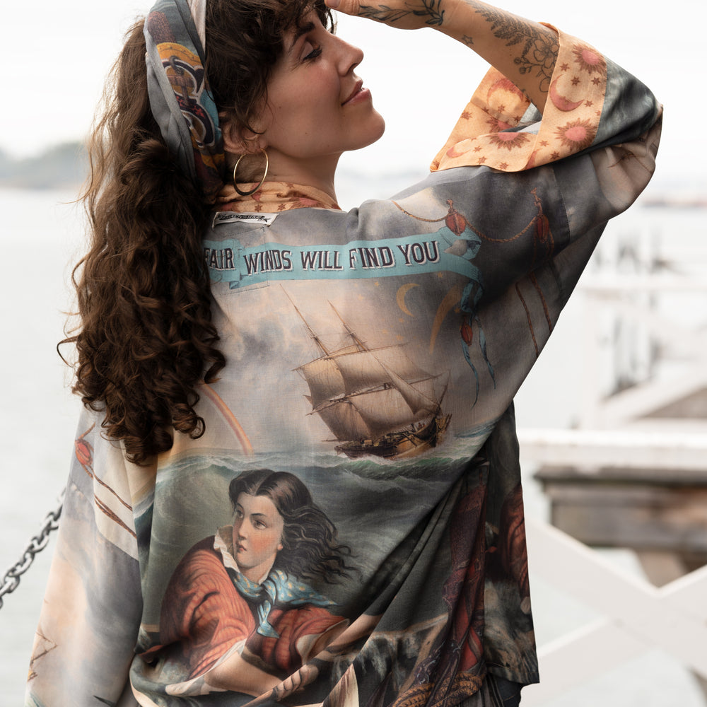 
                  
                    Model wearing the Hold Fast Pixie Duster featuring a Victorian woman rowing through a storm, seagulls, and rainbow horizon – Market of Stars.
                  
                