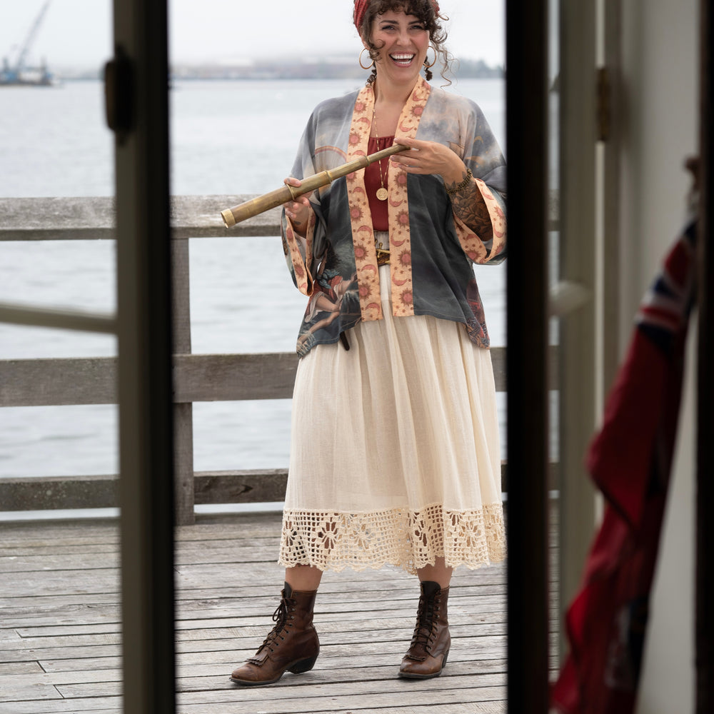 
                  
                    Model wearing the Hold Fast Pixie Duster featuring a Victorian woman rowing through a storm, seagulls, and rainbow horizon – Market of Stars.
                  
                