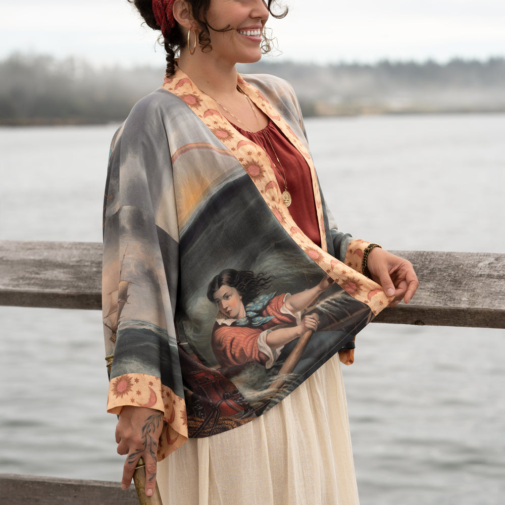 
                  
                    Model wearing the Hold Fast Pixie Duster featuring a Victorian woman rowing through a storm, seagulls, and rainbow horizon – Market of Stars.
                  
                