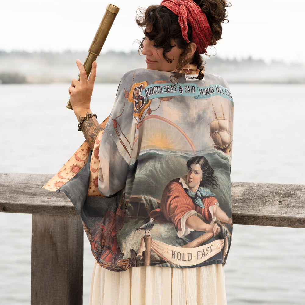 
                  
                    Model wearing the Hold Fast Pixie Duster featuring a Victorian woman rowing through a storm, seagulls, and rainbow horizon – Market of Stars.
                  
                