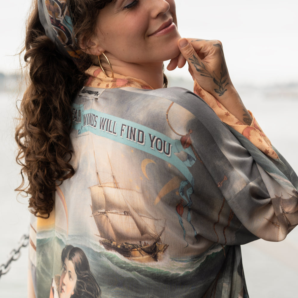 
                  
                    Model wearing the Hold Fast Pixie Duster featuring a Victorian woman rowing through a storm, seagulls, and rainbow horizon – Market of Stars.
                  
                