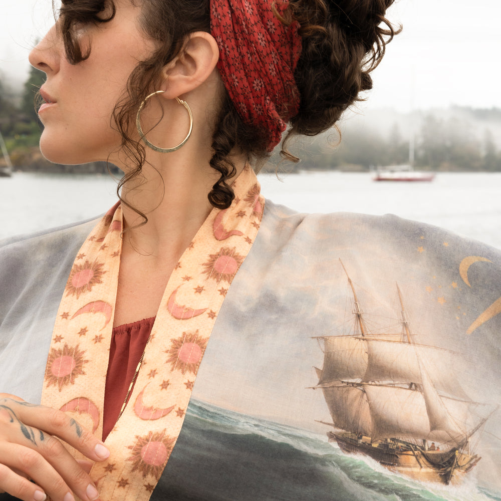
                  
                    Model wearing the Hold Fast Pixie Duster featuring a Victorian woman rowing through a storm, seagulls, and rainbow horizon – Market of Stars.
                  
                