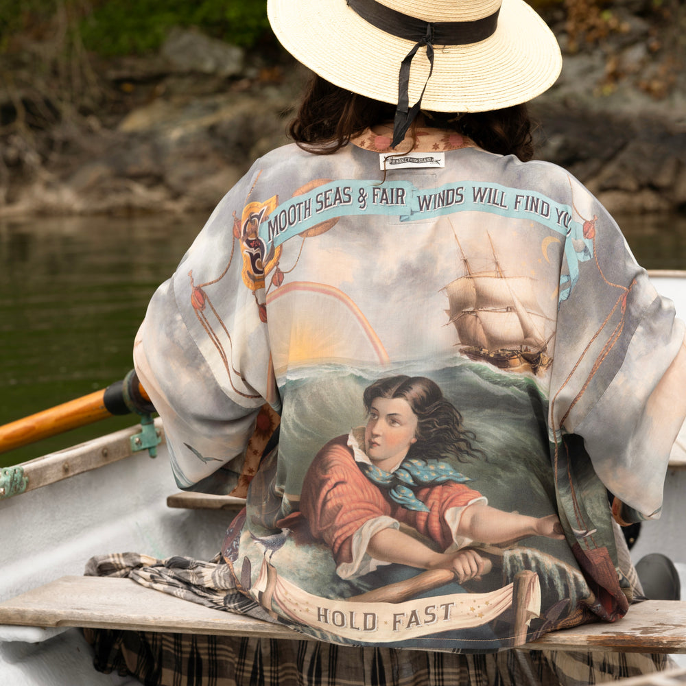 
                  
                    Model wearing the Hold Fast Pixie Duster featuring a Victorian woman rowing through a storm, seagulls, and rainbow horizon – Market of Stars.
                  
                