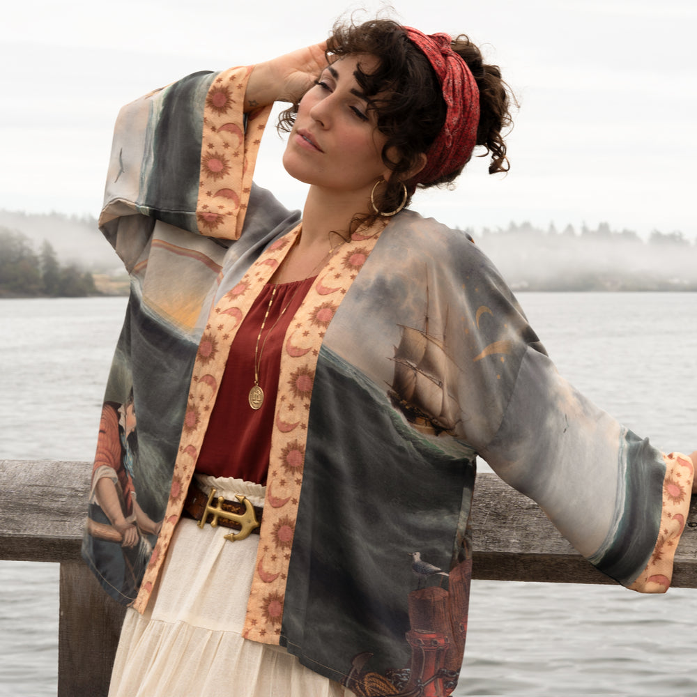 
                  
                    Model wearing the Hold Fast Pixie Duster featuring a Victorian woman rowing through a storm, seagulls, and rainbow horizon – Market of Stars.
                  
                