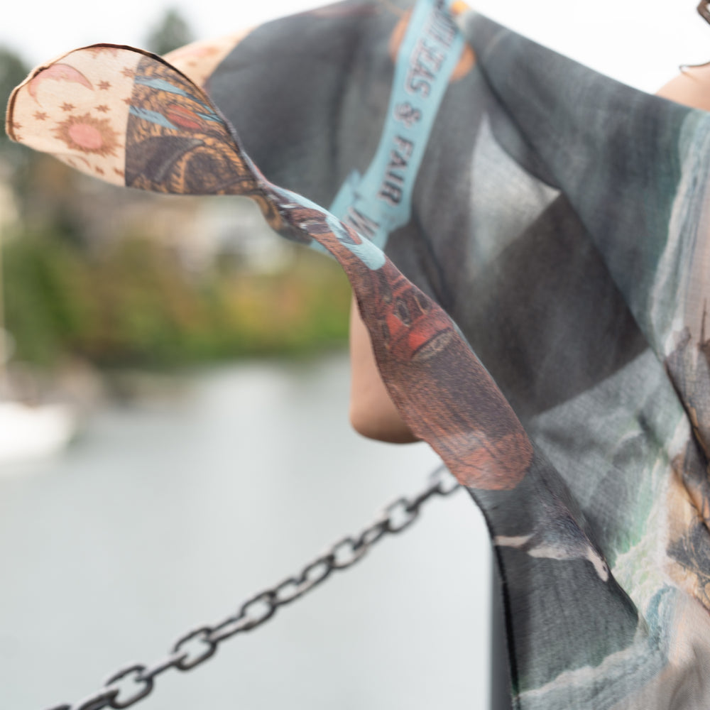 
                  
                    Model wearing the Hold Fast bamboo viscose scarf featuring a Victorian woman bravely rowing through a storm, seagulls, and rainbow horizon – Market of Stars.
                  
                