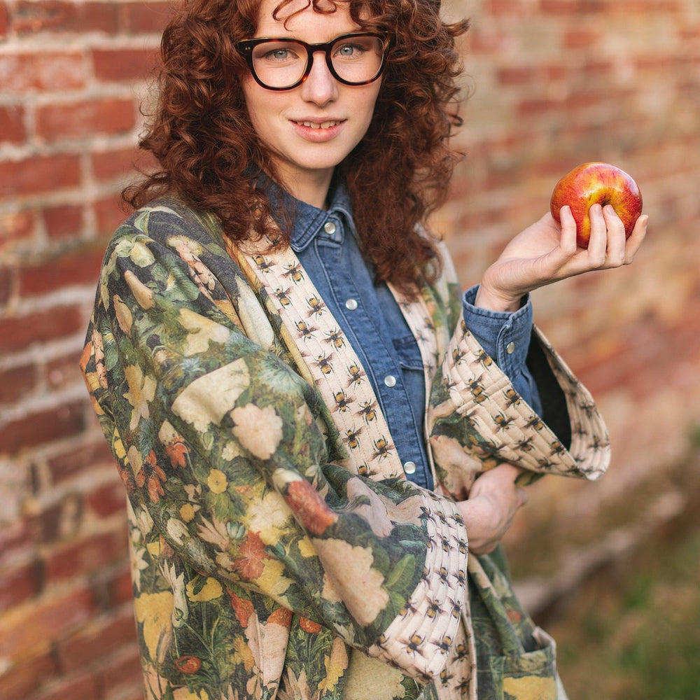 
                  
                    Model wearing the I Dream in Flowers Cottage Cardigan featuring painterly floral artwork and Victorian bumblebee trim, perfect for cozy layering – Market of Stars
                  
                