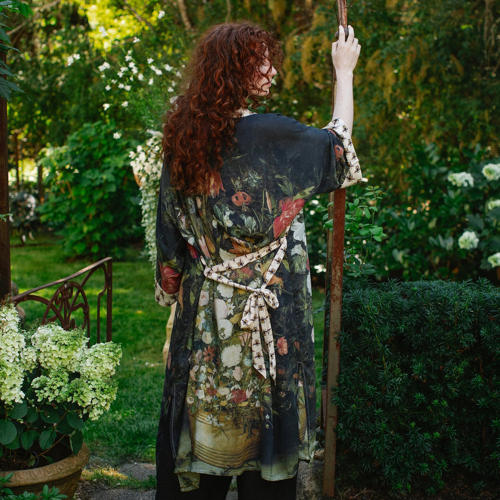 
                  
                    Model wearing the I Dream in Flowers Opera Duster featuring floral oil painting by Jan Brueghel and Victorian bumblebee trim – Market of Stars.
                  
                