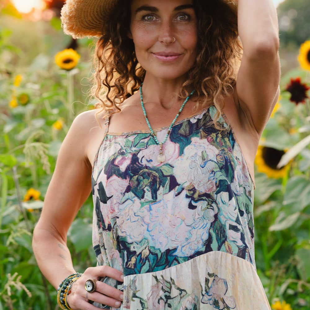 
                  
                    Model wearing bamboo viscose slip dress featuring Van Gogh artwork and quote, with painted blossoms, book, sun, and eye in rich sunny tones of jade and gold - Market of Stars
                  
                