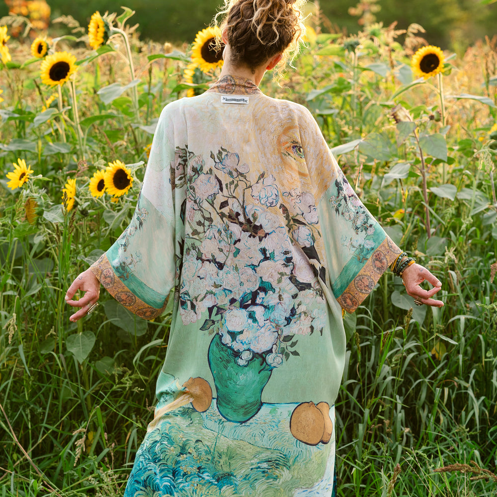 
                  
                    Model wearing long kimono duster featuring Van Gogh artwork and quote, with painted blossoms, book, sun, and eye in rich tones of jade and gold - Market of Stars
                  
                