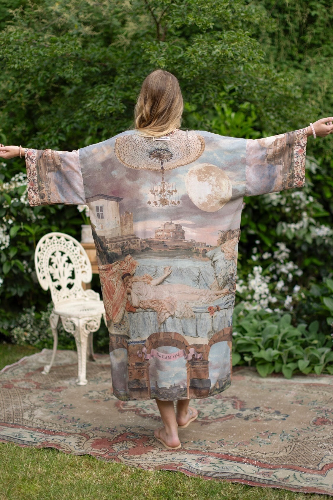 Model standing in airy Imaginarium opera duster featuring layered dreamscape art, candlelit chandelier, and sleeping muse inspired by Victorian paintings – Market of Stars